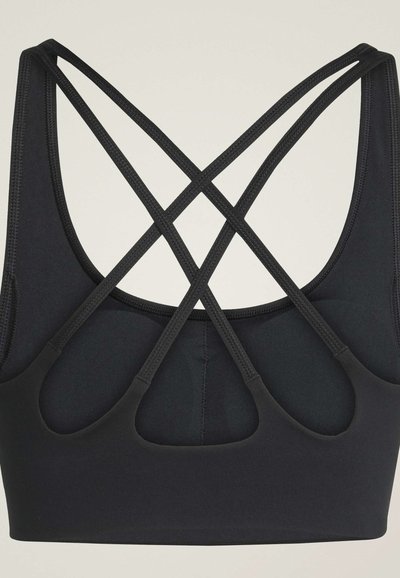 Reggiseno sportivo nero con doppie spalline sottili che si incrociano a forma di X e dettaglio sagomato sulla schiena, mostrato su uno sfondo chiaro.