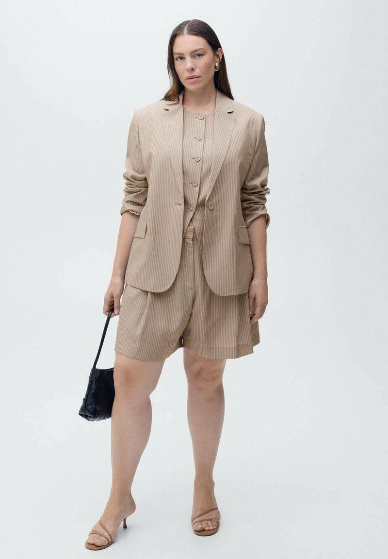 Blazer beige a righe e pantaloni corti coordinati, tessuto strutturato, chiusura a un bottone con tre bottoni, accessoriate con una borsa nera.
