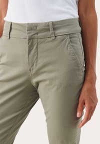 Svijetlozelene hlače od mješavine pamuka sa slim fit krojem, prednjim zatvorenjem na cipzar i bočnim džepovima. Ušivene detalji na struku i rubovima džepova.