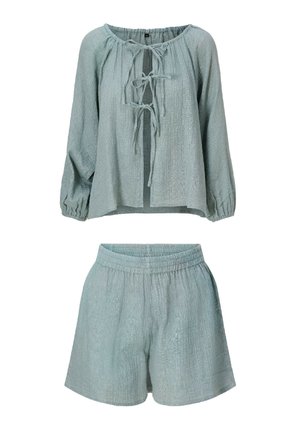 Hellblaues zweiteiliges Outfit aus strukturierter Stoff, langärmliges Oberteil mit Knoten vorn und Shorts mit elastischem Bund, auf weißem Hintergrund dargestellt.