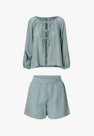 Lichtblauwe tweedelige outfit van gestructureerde stof, met een langärmlige top met strik aan de voorkant en shorts met elastische tailleband, afgebeeld op een witte achtergrond.