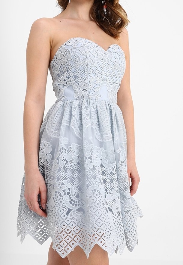 Sukienka bez ramiączek w jasnoniebieskim kolorze z misternymi koronkowymi detalami, dopasowaną górą i rozkloszowanym dołem z falbaniastym wykończeniem oraz kwiatowymi wzorami.