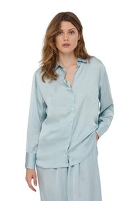 Camicia azzurra in satin con bottoni, maniche lunghe, colletto casual e un orlo posteriore leggermente più lungo, con bottoni perlacei.