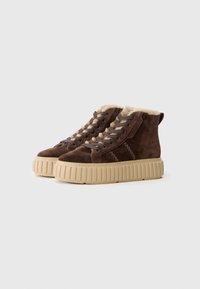 Baskets montantes en daim marron avec doublure en fourrure tan douce, design à lacets et semelles en caoutchouc beige chunky avec texture striée.
