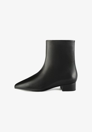 Bottines en cuir noir avec un bout pointu et un petit talon carré. Texture lisse sans quincaillerie visible ni éléments décoratifs.