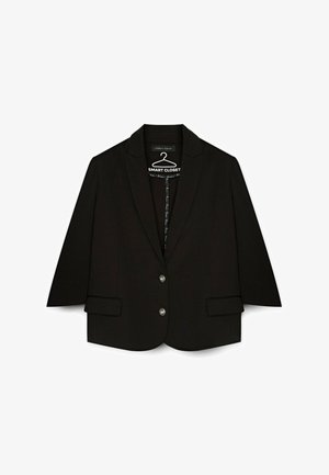 Blazer nero con un design sartoriale, rever a punta, due bottoni e tasche laterali. Realizzato in un tessuto morbido con una forma strutturata.
