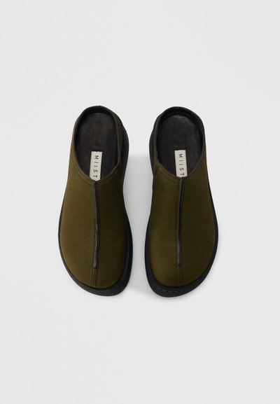 Πράσινα παπούτσια τύπου slip-on με απαλό, ματ φινίρισμα, με κεντρικό ραφτό και μαύρη λαστιχένια σόλα, σχεδιασμένα για εύκολη εφαρμογή και άνεση.