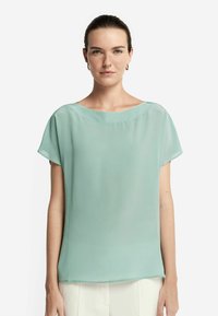 Helle, mintgrüne Bluse aus einem fließenden, transparenten Stoff. Verfügt über einen weiten runden Ausschnitt und kurze Ärmel. Glattes, minimalistisches Design.