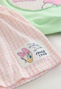 Zöld pulóver bordázott mandzsettákkal, rózsaszín-fehér kockás anyagból, "Daisy Duck Since 1940" felirattal és hímzett karakterrel.