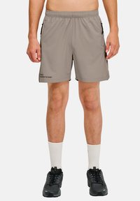 Grå lätta shorts med elastisk midja, sidofickor med dragkedja och tryckta grafiker på underbenet. Bärs med vita strumpor och svarta skor.
