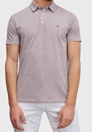 Mann trägt ein kurzärmeliges, hellviolettes, gemustertes Poloshirt mit Knöpfen und kleinem besticktem Logo, kombiniert mit weißen Hosen.