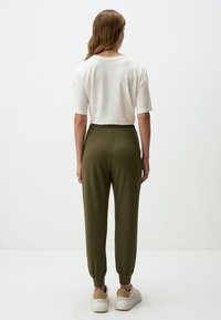 Wit kortmouwen t-shirt met een relaxed fit, gecombineerd met olijfgroene tapered joggers. De joggers hebben een elastische tailleband en afgewerkte zomen.