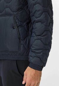 Giacca a vento navy con motivo a rombi, polsini elasticizzati e tasca con bottone a pressione sulla parte frontale. Tessuto morbido e leggero.