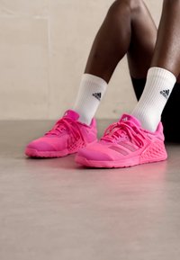 Scarpe da atletica rosa con materiali in rete e sintetici. Le caratteristiche includono lacci, suola testurizzata e tre strisce orizzontali sui lati.