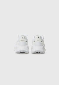 Baskets de sport blanches avec un dessus en mesh texturé, un talon renforcé et une semelle en caoutchouc. Présente une marque minimale et un design épuré et moderne.