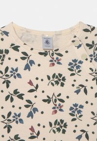 Camicia di cotone color crema chiaro con motivo floreale verde, blu e burgundy, dotata di bottoni a pressione sulla spalla e colletto a coste.