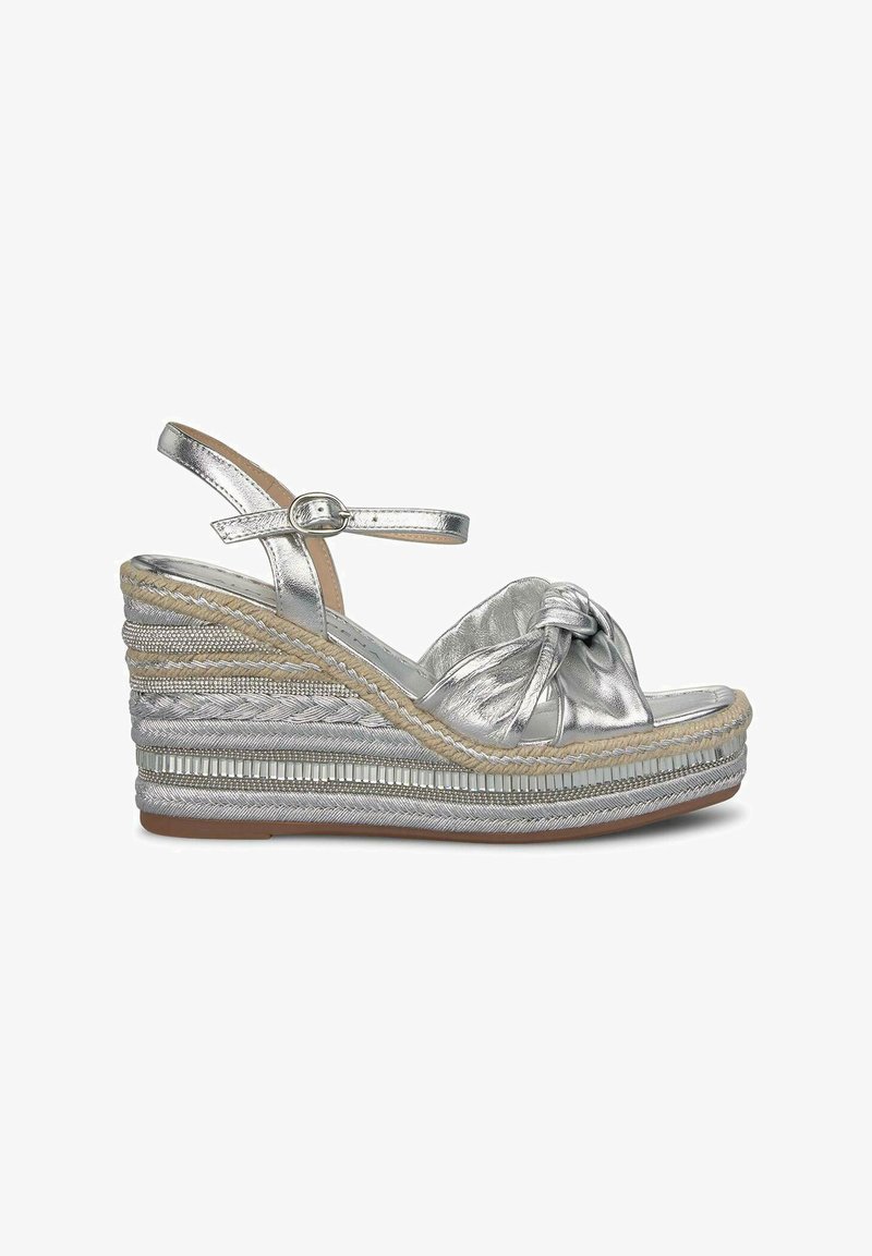 Sandali wedge argentati con design annodato, tomaia metallizzata, dettagli in juta intrecciata e bande di accento testurizzate. Fibbia regolabile alla caviglia.