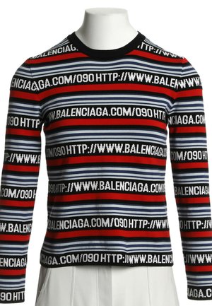 Langærmet stribet sweater med røde, blå og sorte bånd og gentaget hvid tekst "HTTP://WWW.BALENCIAGA.COM/090" på stoffet.