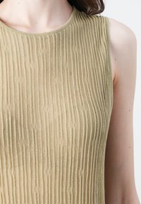 Strikket tank topp i myk beige med vertikal ribbet tekstur. Har en klassisk rund halslinning og er uten ermer.