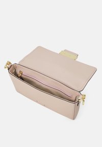 Beige leather handbag with a structured shape, gold hardware, and a zippered compartment. Interior features a pink lining and storage pocket.