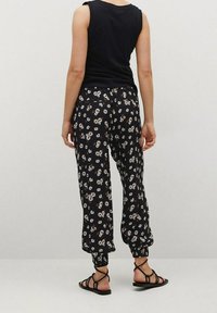 Haut sans manches noir associé à un pantalon fleuri noir et blanc à motifs. Le pantalon présente une taille élastique et des ourlets fuselés avec une texture douce.