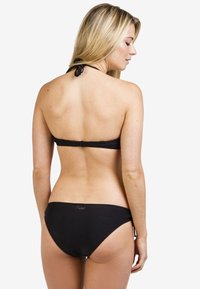 Zwart bikini set bestaande uit een haltertop met strikjes en klassieke slipjes. Glad textuur, minimalistisch ontwerp, met merkimpressie op de achterkant.