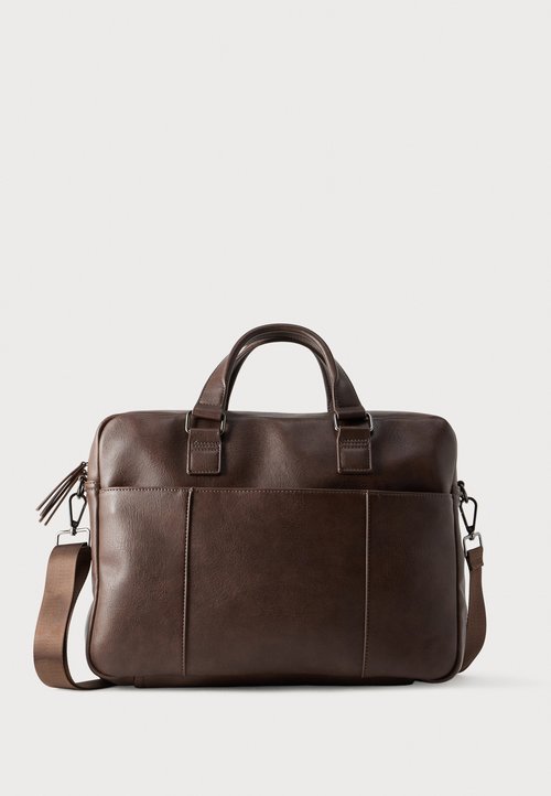 Sac en cuir marron avec deux poignées supérieures, bandoulière réglable et poches avant. Texture lisse avec des détails de couture minimaux.
