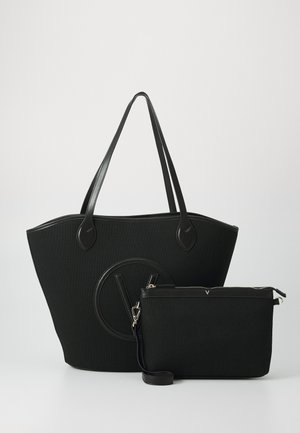 Black tote bag with textured exterior, featuring a circular logo and dual handles. Includes matching zippered pouch with detachable strap.