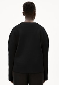 Svart oversized tröja med ribbad halsringning, långa ärmar och textilstruktur. Designen är enkel och oförskönad, med en avslappnad passform.