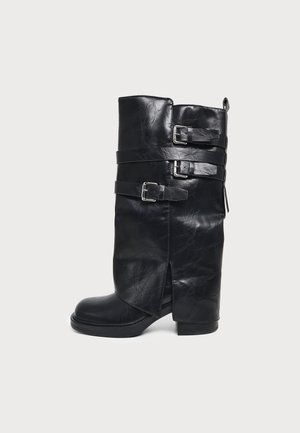 Botte haute en cuir noir à bout arrondi, avec un talon bloc bas et trois brides décoratives à boucles.