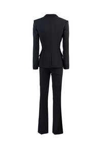 Completo su misura nero con blazer aderente e pantaloni svasati. Il tessuto è liscio con linee pulite e dettagli di cucitura sottili.