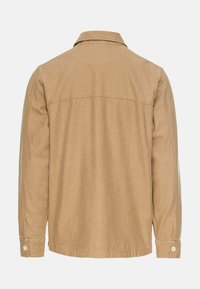 Beige langiemanige shirt met een kraag, heeft een rechte snit, zijnaden en knoopsluitingen op de manchetten. Glad stofoppervlak.