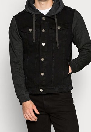 Schwarze Jeansjacke mit integrierter grauer Kapuzenjacke, mit Knöpfen zu schließen, zwei Brusttaschen und Seitentaschen; glatte Textur und kontrastierende Materialien.