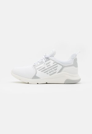 Baskets blanches avec tige en mesh, accents gris et col rembourré. Présente des lacets et une semelle texturée pour une meilleure adhérence et un meilleur soutien.