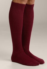 Bordeauxrode kniekousen met een ribbelstructuur, gemaakt van zacht materiaal, met een nauwsluitende bovenkant en gladde teendoeken.