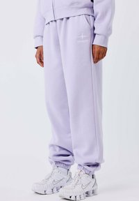 Lila sweatpants met elastische boorden en zijzakken, voorzien van een witte geborduurde logomotief. Zachte, geborstelde katoenen stof.
