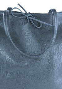 Grijze lederen tote bag met een textuurovervlak, voorzien van twee ronde handvatten en een gestrikte sluiting aan de bovenkant. Minimalistisch ontwerp.