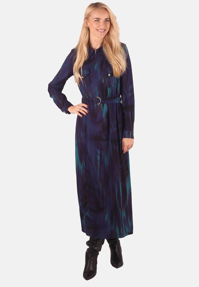 Long-sleeve, collared dress in dark blue with green and black abstract patterns. Features a belted waist and buttoned chest pockets.