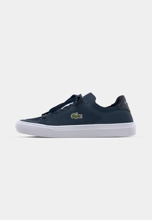 Navy blue mesh sneakers with a white rubber sole, featuring a green Lacoste crocodile logo and flat laces, designed for comfort and breathability.