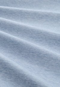Tessut de culoare albastru deschis cu o textură netedă, prezentând pliuri diagonale și linii subtile, indicând un material din bumbac sau o amestecare cu bumbac.