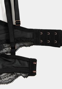 Sostén negro con material de malla, delicados bordes de encaje, tirantes ajustables y un cierre de gancho y ojo con acentos de oro rosa.