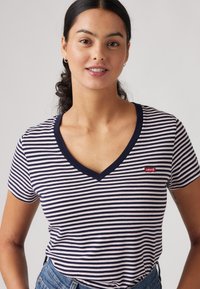 Camiseta de manga corta a rayas con rayas horizontales en azul marino y blanco, escote en V y un pequeño logo rojo de Levi's cerca del hombro izquierdo.