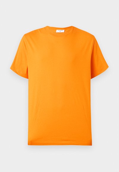 T-shirt di cotone arancione brillante a maniche corte con collo tondo, posata su uno sfondo grigio chiaro.
