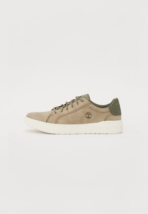 Sneaker beige in suede con dettagli verde oliva, design con lacci e suola in gomma. Presenta un piccolo logo sul lato.
