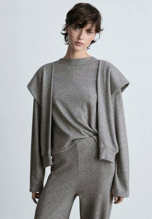 Grauer Strickoberteil mit kurzen, strukturierten Ärmeln, kombiniert mit passenden hochgeschnittenen Hosen. Weicher Stoff und lässiges Design.