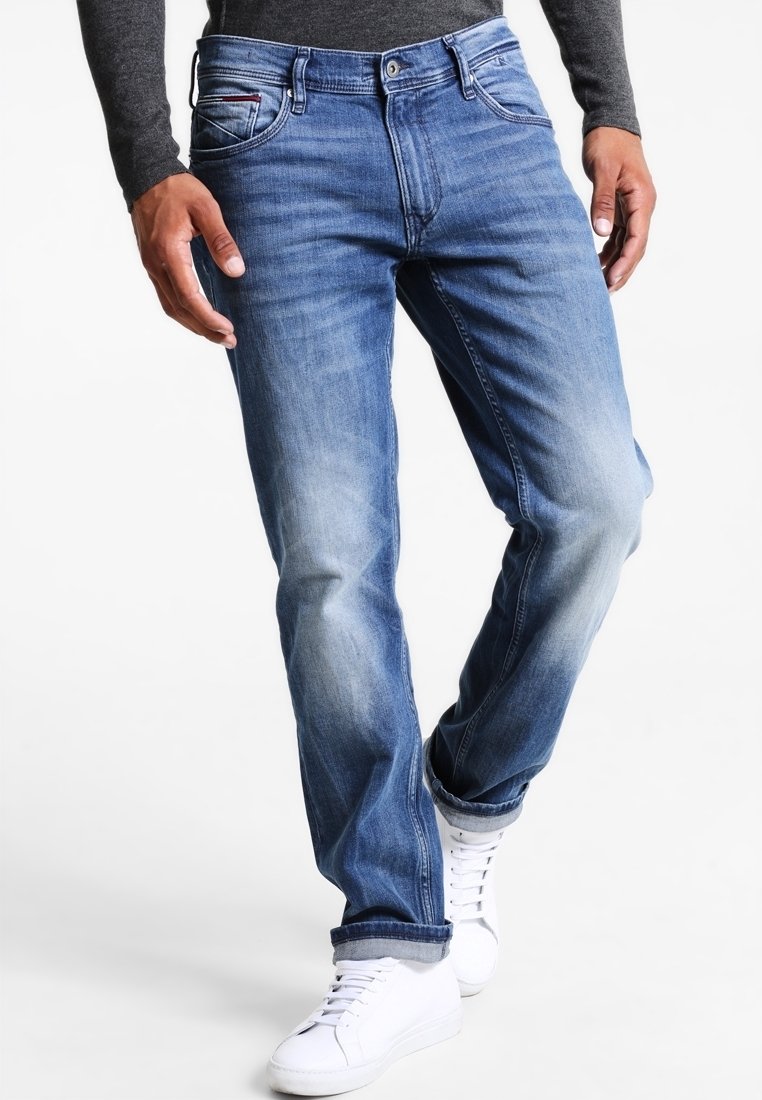 Ljusblå denim jeans med rak benavskärning, med en blekt finish, fem fickor och en knappgylf, som bärs med vita sneakers.