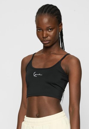 Black cropped tank top made of stretchy fabric, featuring slim straps and a white logo detail on the front.