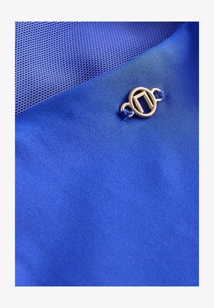 Plava tkanina s glatkom teksturom koja se ističe tkanom mrežastom površinom. Zlati ukrasni kopča naglašava dizajn, povećavajući vizualnu zanimljivost.