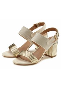 Beige hoge sandalen met een brede herringbone-patroonriem en een metalen gouden geribbelde voorkant; blokhak met gestructureerde accenten.