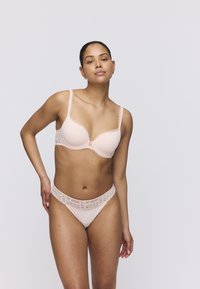 Light pink bra and matching thong made of smooth fabric with floral lace accents along edges and straps. Cups feature a seamless design.